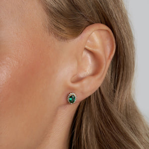 Introducing the 14K Gold Oval Shaped Stud Emerald Earrings, adorned with vintage oval-cut green gemstones and bordered by delicate round white diamonds. These earrings boast a polished finish and are secured with a post and butterfly back fastening.