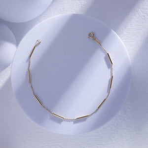 Introducing the 14K Gold Minimal Station Bracelet by RundaJewelryUs: a delicate design featuring a thin chain accented with small, evenly spaced tube-shaped beads in lustrous 14K gold. This elegant piece is securely fastened with a traditional lobster claw closure.