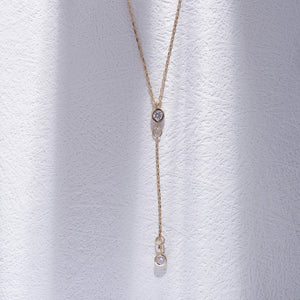 Introducing the 14K Gold Y Minimal Diamond Chain Necklace by RundaJewelryUs, a delicate piece showcasing two small round diamond pendants elegantly spaced along the chain. One pendant drapes lower for a sophisticated layered look against a plain white background.