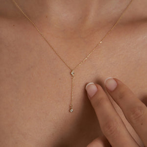 Introducing the 14K Gold Y Minimal Diamond Chain Necklace by RundaJewelryUs, a delicate piece showcasing two small round diamond pendants elegantly spaced along the chain. One pendant drapes lower for a sophisticated layered look against a plain white background.