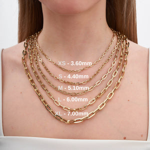 A collection of gold chains, highlighted by the exquisite 14K Gold Paperclip Chain Necklace, is arranged in a semi-circle. Each piece showcases distinct link sizes and styles characteristic of Italian design jewelry. They are layered from smallest to largest, creating a cascading effect against the white background.