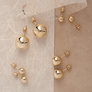 The 14K REAL Gold Ball Stud Earrings from RundaJewelryUs are showcased against a white backdrop. One earring is displayed flat, while the other reveals the ball and post with its butterfly back attached, emphasizing their hypoallergenic construction.