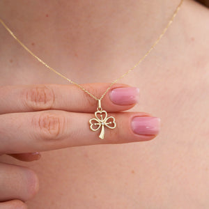 The 14K Gold Clover Pendant Necklace boasts heart-shaped leaves and a central Cubic Zirconia gemstone, with a delicate chain enhancing the gold hue for an exquisite accessory.