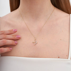 The Love Minimal Gold Arrow Necklace is crafted from 14k gold and showcases a bow charm pendant elegantly adorned with small diamonds along its curve. Its thin and delicate chain ensures a touch of elegance, while the hypoallergenic material guarantees comfort for sensitive skin.