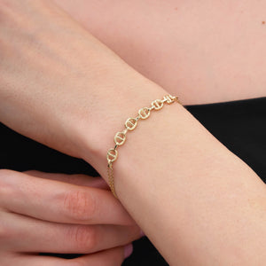 Introducing the 14K Gold Flat Mariner Anchor Chain Bracelet! Featuring intricate decorative links, this piece boasts a centerpiece of elegant interlocking oval shapes. The small clasp includes an adjustable chain for a customizable fit, making it an ideal choice for stylish layering.