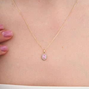 The 14K Gold Rose Quartz Necklace features an oval-shaped pendant with a stunning pink rose quartz gemstone, surrounded by a halo of small white diamonds. Its delicate chain elegantly contrasts with the vibrant stones, symbolizing healing relationships and exuding sophistication.