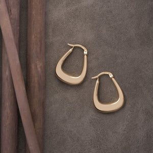 Presenting the 14K Gold Thick Hoop Earrings, these pieces boast a modern, slightly tapered design in yellow gold. Set against a plain white backdrop, one earring is displayed face-on while the other is shown from a side angle to highlight their shiny and smooth finish. Ideal for those in search of hypoallergenic jewelry.