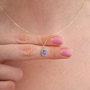 Product Description: The 14K Gold Amethyst Necklace features an oval-shaped amethyst pendant encircled by a halo of shimmering zirconia stones. Its elegant design is mesmerizing, set against a pure white backdrop.