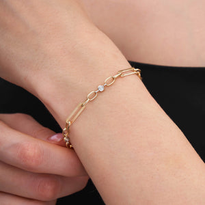 The 14K Gold Paperclip Link Chain Bracelet is a refined piece crafted from solid gold, showcasing an elegant design that alternates between elongated paperclip links and small circular links. It is embellished with three evenly spaced, small round diamonds along the chain, making it perfect for layering. The bracelet secures with a lobster clasp.