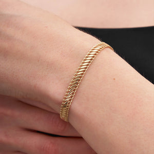 A 14K gold handmade bracelet from RundaJewelryUs, featuring a snake design and a lobster clasp, is elegantly laid flat on a white background.