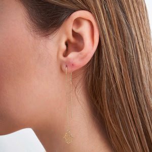 Eco-friendly handcrafted 14K Yellow Gold Long Threader Earrings adorned with delicate Hamsa hand charms are showcased against a plain white background.