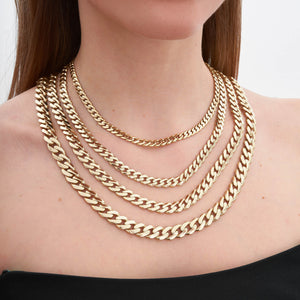 An up-close view of the 14K Gold Miami Cuban Curb Link Chain Necklace is showcased against a plain white background. This hypoallergenic piece features a polished surface that reflects light, accentuating its intricate interlocking pattern.