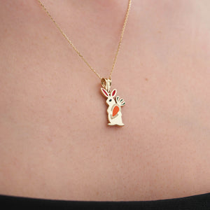 The 14K Gold Cute Rabbit Holding Carrot Necklace by RundaJewelryUs features a delicate rabbit-shaped pendant crafted from 14K gold, with vibrant red and orange enamel accents on its ears and body. Ideal for those who love distinctive jewelry, this piece adds a whimsical touch to any collection.