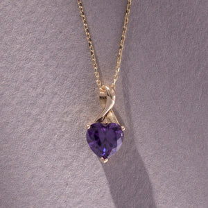 The 14K Solid Gold Amethyst Heart Pendant Necklace features a heart-shaped amethyst elegantly set in a sophisticated twist design, suspended from a delicate gold chain.