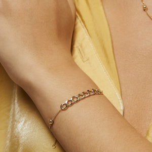 The 14K Solid Gold Bracelet from the Harmony Collection elegantly combines curb link designs with delicate smaller links on each side. Crafted in hypoallergenic 14K solid gold, it features a circular clasp and a round charm engraved with a symbol, available in your choice of yellow, white, or rose gold.