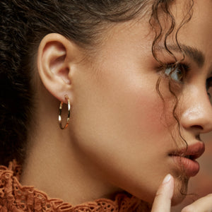 The 14K Gold Round Hoop Earrings from the Harmony Collection by RundaJewelryUs are showcased. One earring is pictured facing forward, accentuating its circular form, while the other is displayed from the side, highlighting its sleek profile and contemporary design.