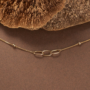 The 14K Solid Gold Triple Interlocking Unity Bracelet from the Harmony Collection boasts three prominent interlocking links at the center, accompanied by small circular charms and an adjustable clasp. Model No X5B201376 is distinguished by its intricate chain and charm detailing, featuring a hypoallergenic design ideal for those with sensitive skin.