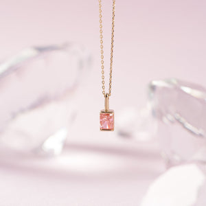 The 14K Gold Pink Rose Quartz Necklace features a rectangular pink rose quartz pendant on a delicate 14K solid gold chain, symbolizing self-love, and is showcased against a white background.