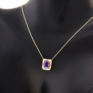 The 14K Solid Gold Amethyst Necklace, ideal for a February birthstone gift, showcases a rectangular pendant adorned with a vibrant purple gemstone. Surrounded by small, clear stones and hanging from a delicate chain, this handcrafted piece embodies elegance and charm.