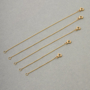 An elegant 14K solid gold accessory featuring a minimalist design with small interconnected links, discreet clasp, and ring fastener, perfect as a necklace or bracelet chain extender.