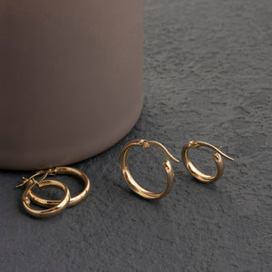 A set of radiant 14K solid gold hoop earrings for men, featuring one earring shown from the side and the other displayed open to showcase its clasp. These meticulously handcrafted pieces offer a smooth and polished finish, effortlessly merging elegance with timeless style.