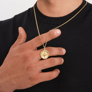 The 14K Solid Gold Compass Necklace for Men showcases a circular pendant with a raised compass design, crafted from solid gold. Its textured edges and polished finish add elegance, while it gracefully hangs on a delicate chain.