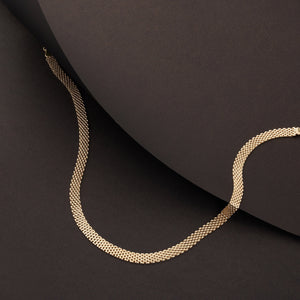 A close-up image highlights a 14K real solid gold Bismarck chain necklace for men, featuring a textured, woven design. The necklace is elegantly arranged in a gentle loop against a plain white background.