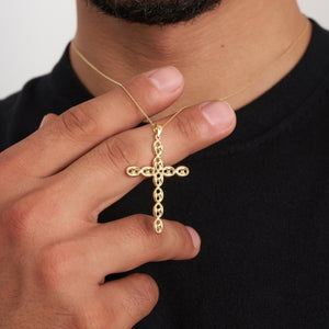 The 14K Solid Gold Puffed Anchor Mariner Cross Necklace for Men showcases a cross pendant adorned with delicate, oval-shaped patterns. This exquisite piece of Christian jewelry gracefully sits on a classic chain, highlighted against a white background.