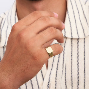 Introducing the 14K Solid Gold Engraved Signet Ring For Men: a stunning piece of jewelry featuring a smooth, rectangular face and a band with an intricate grid-like pattern. Its engraved finish beautifully reflects light on its surface.