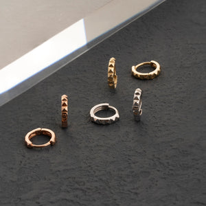 Featuring a geometric pyramid pattern, these tiny hoop earrings in 14K solid gold are showcased with one earring from the side and the other from the front on a simple white background. Perfect for those in search of stylish men's jewelry options.