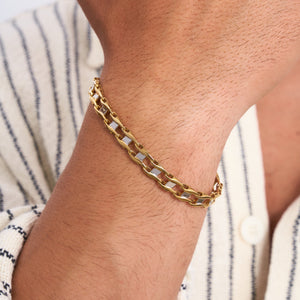 The 14K Solid Gold Classic Bracelet for Men showcases a lobster claw clasp and stackable interlocking links. Photographed against a plain white background, its polished and reflective surface is beautifully highlighted.