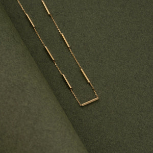 The 14K Solid Gold Bar Station Chain Necklace for Men features minimalist cylindrical bead accents evenly spaced along the fine chain, creating a simple and elegant circular design.