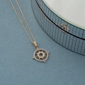 Introducing the 14K Gold North Star and Compass Graduation Necklace, featuring a sunburst pendant crafted from solid 14K gold. This intricately designed piece is adorned with small clear stones, capturing a bright elegance reminiscent of the North Star's guiding light.