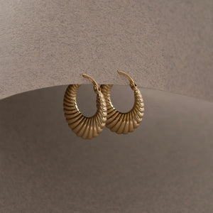 A pair of 14K Real Gold Shrimp Hoop Earrings features a chunky design with a ribbed texture. One earring is showcased from the side, while the other faces forward, emphasizing the intricate details of this statement accessory.