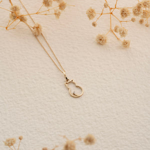 Discover the 14K Solid Gold Cat Necklace, a must-have for cat enthusiasts and summer jewelry collections. Its elegant chain displays a cat outline pendant adorned with a small gemstone at the tip of the tail, all set against a white background.