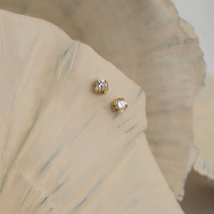 A pair of sophisticated 14K Solid Gold 2.50 mm Stud Earrings, showcasing a single round-cut diamond secured in a sleek prong setting. One earring presents the front view of the diamond, while the other reveals both the back and butterfly clasp against a plain white background.